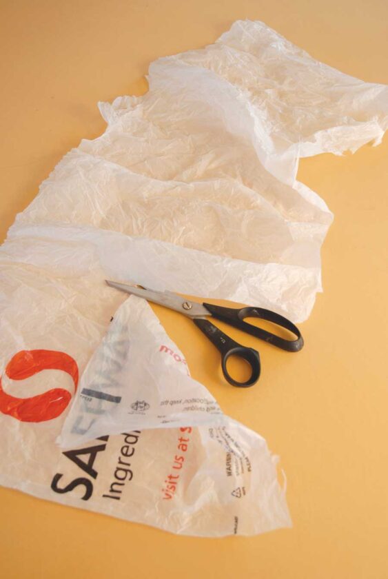Cut off bottom seam and handles of bags. Cut off printed area to create large expanses of unprinted plastic. Cover work surface with a towel, then a sheet of parchment. Heat iron to medium.
